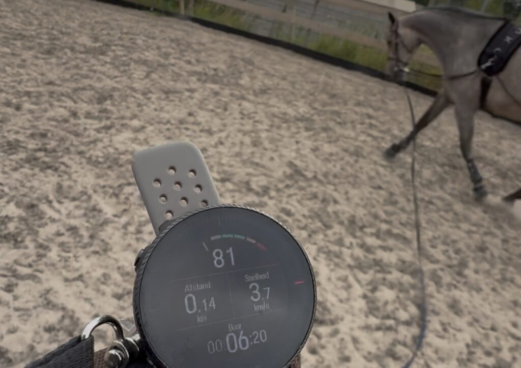 Hartslagmeter met dravend paard op de achtergrond